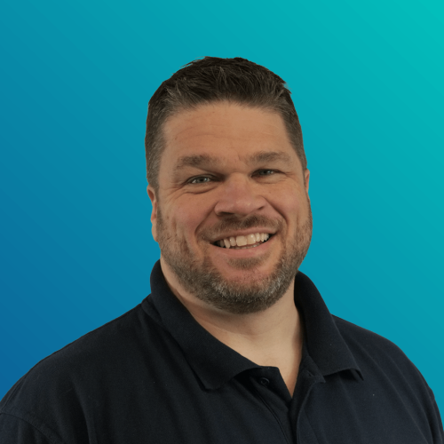 Smiling man in a black polo shirt against a teal gradient background.
