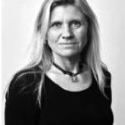 Portrait of a woman with long blonde hair wearing a black top, looking at the camera.